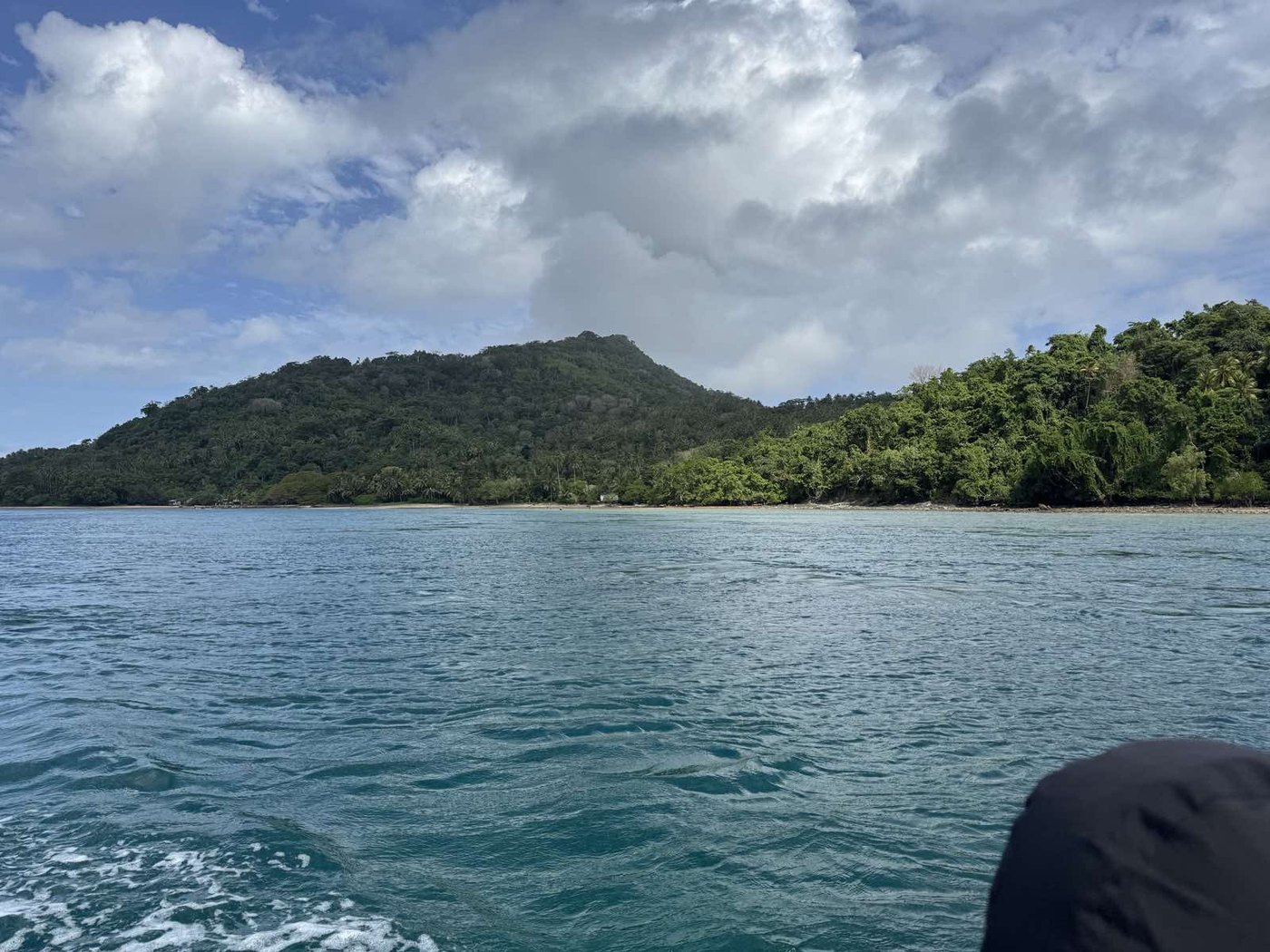 A coastal shoreline and green hillside in Milne Bay Province
